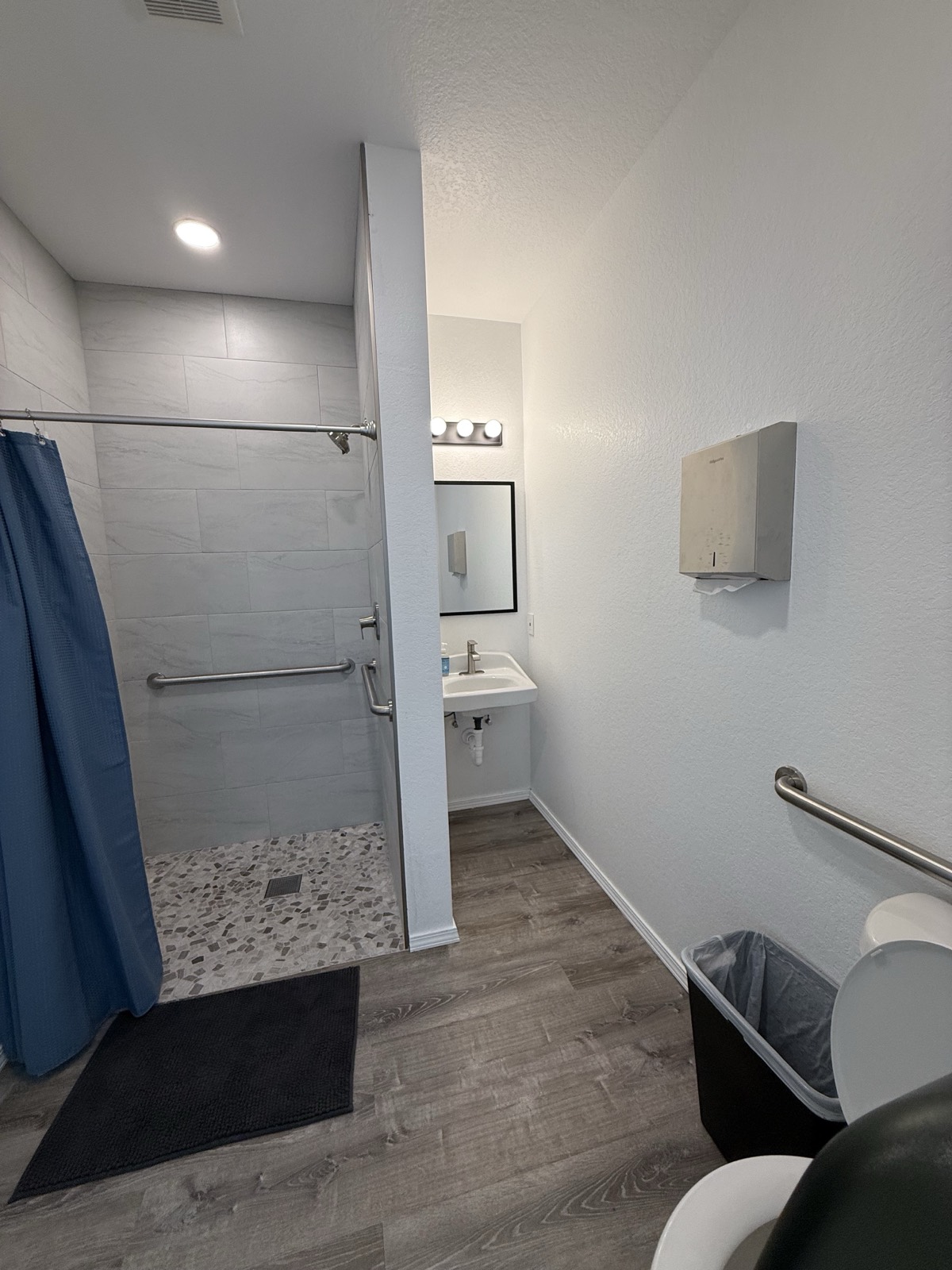 Clean tiled walk-in shower with grab bars in the clubhouse restroom at Shade Stop RV
